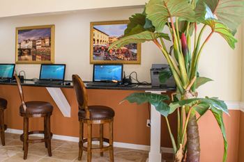 a desk with three laptops and two stools at Lakeside Gardens, Daytona, FL